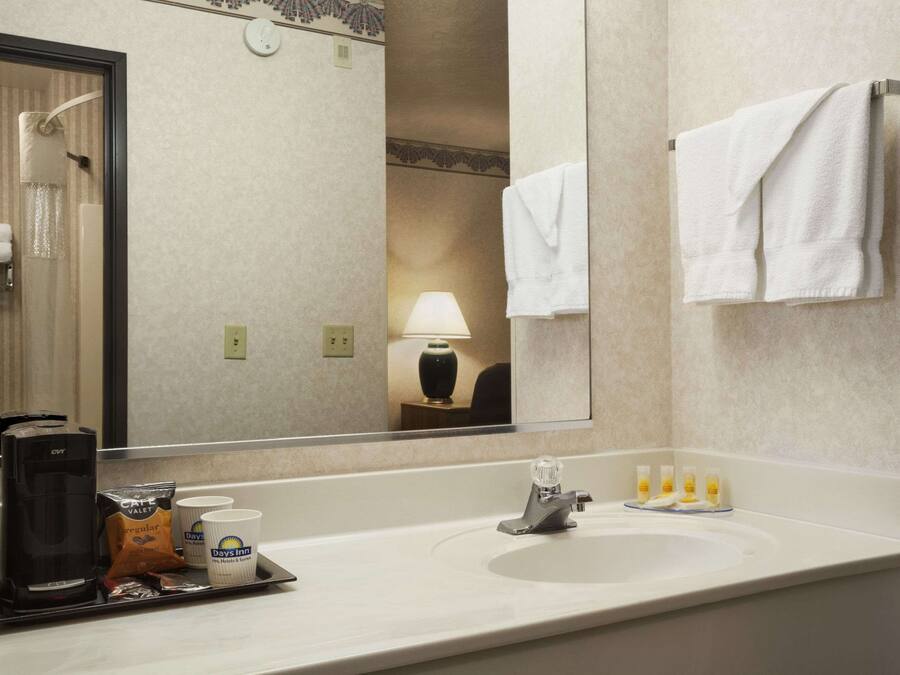 Un baño de hotel con un espejo grande, un lavamanos, una cafetera y artículos de tocador.