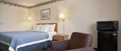 Een hotelkamer met een bed, twee bedlampen, een televisie en een kleine koelkast.