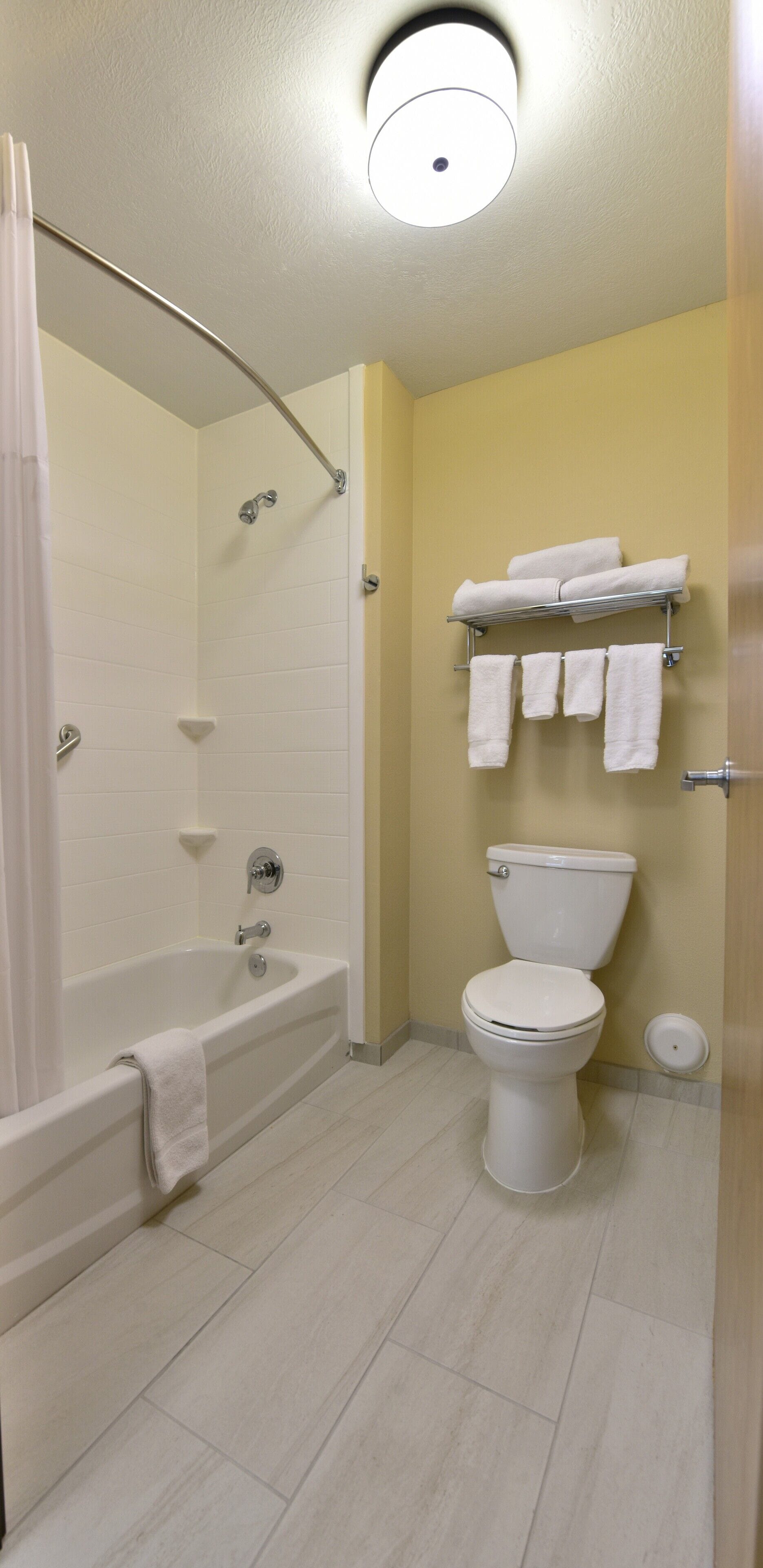 A bathroom with a bathtub, toilet, and a towel rack.