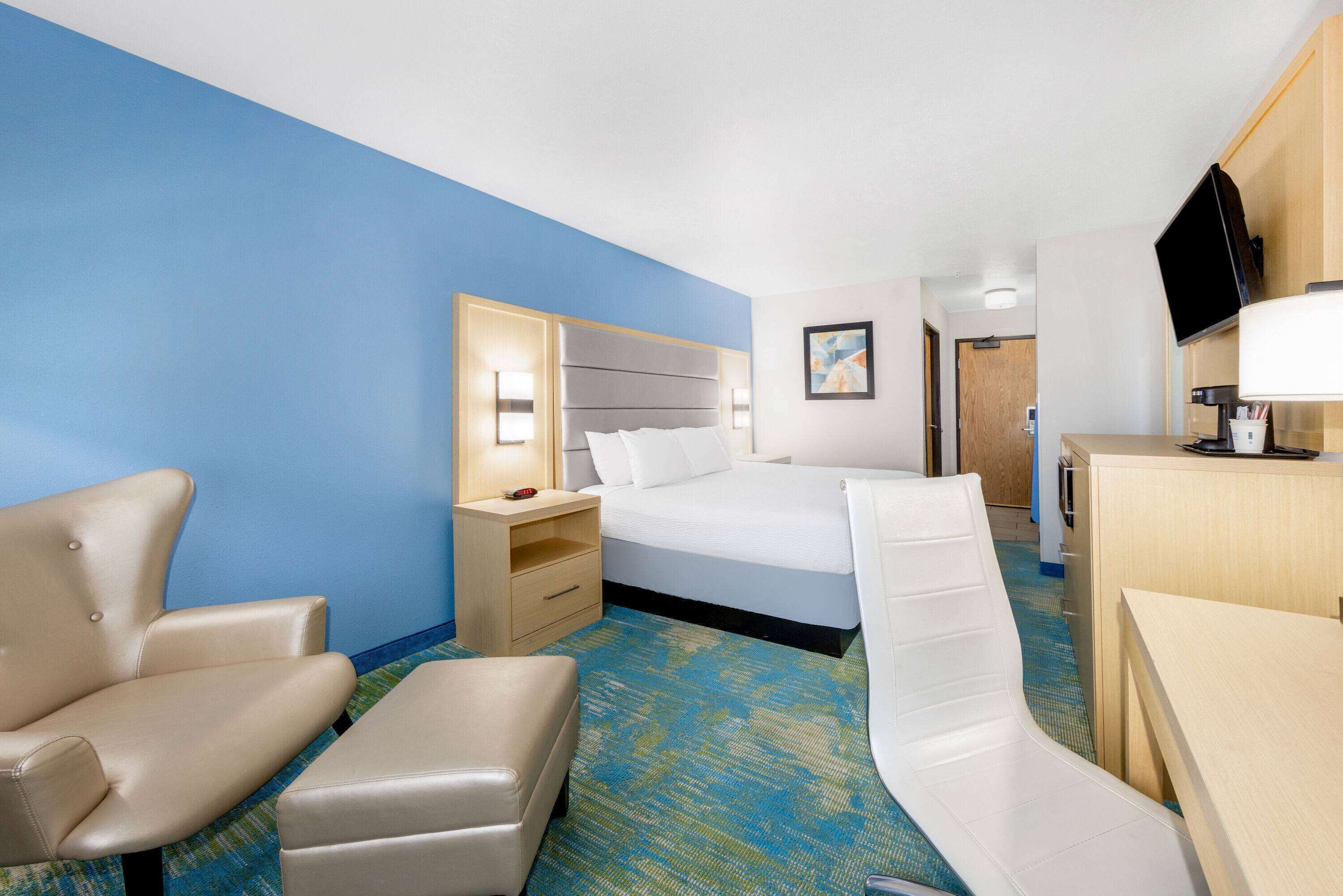 A hotel room with a bed, a desk, a chair, and a nightstand.