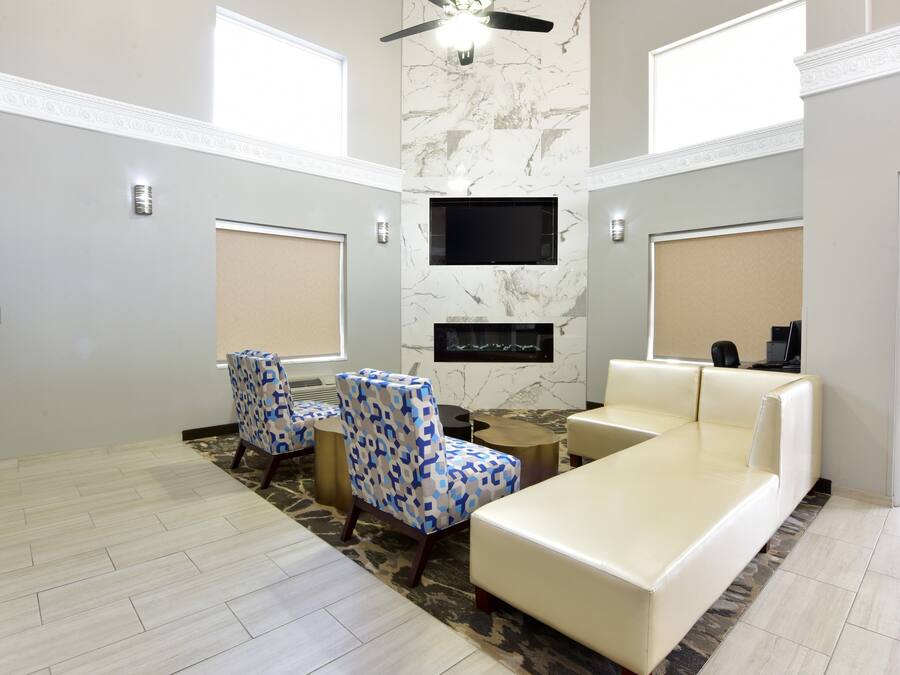 A modern living room with a flat-screen TV, a fireplace, a ceiling fan, and a large window.