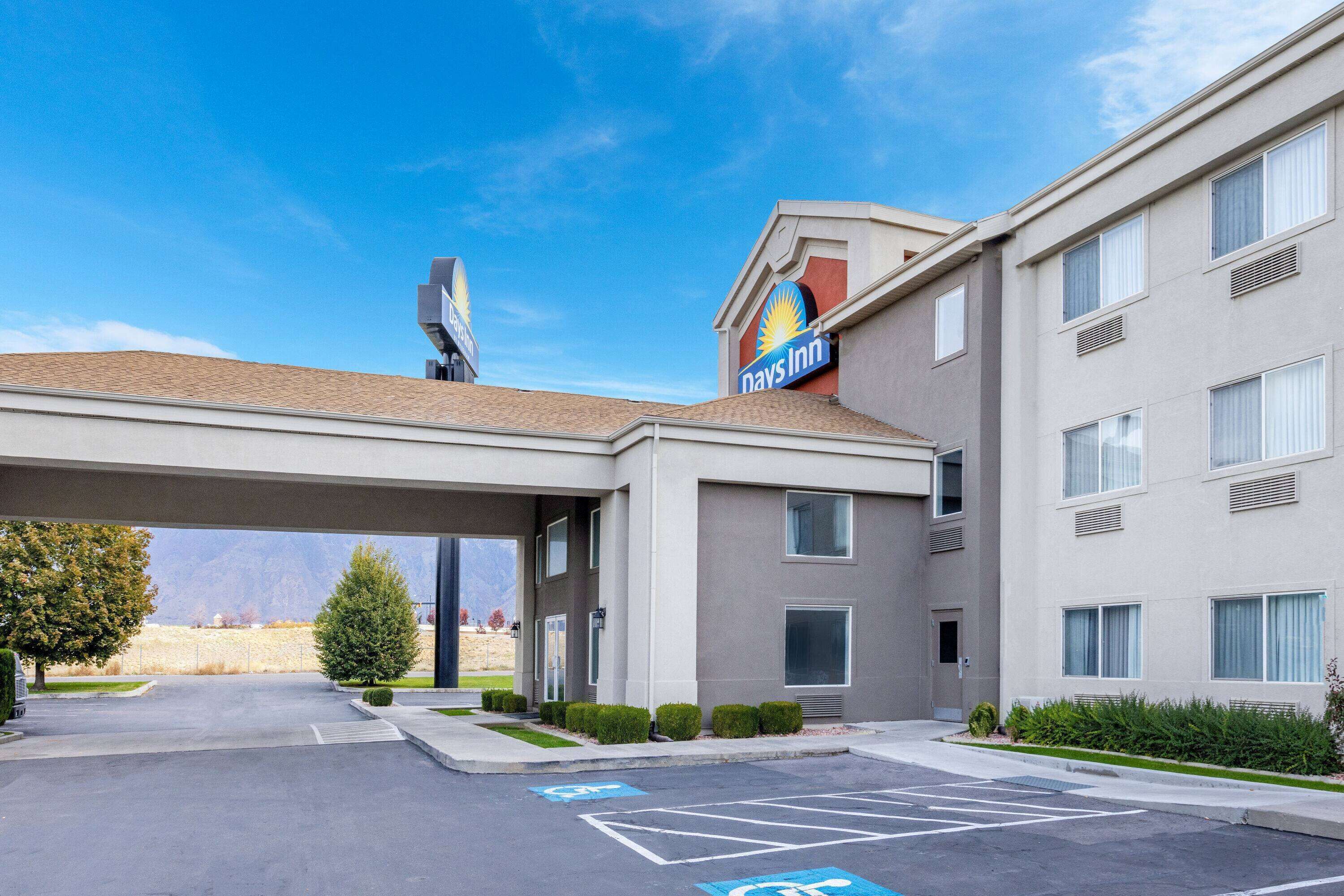 A Days Inn with a covered parking area, a clear sky, and a mountainous background.