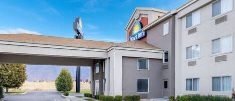 A Days Inn with a covered parking area, a clear sky, and a mountainous background.