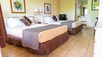 A hotel room with two beds, a desk, a microwave, and a bathroom visible through an open door.