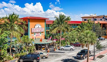 Un hôtel situé en bord de mer, avec une enseigne indiquant « Beach Resorts Hotel & Suites » et un bar de style polynésien.