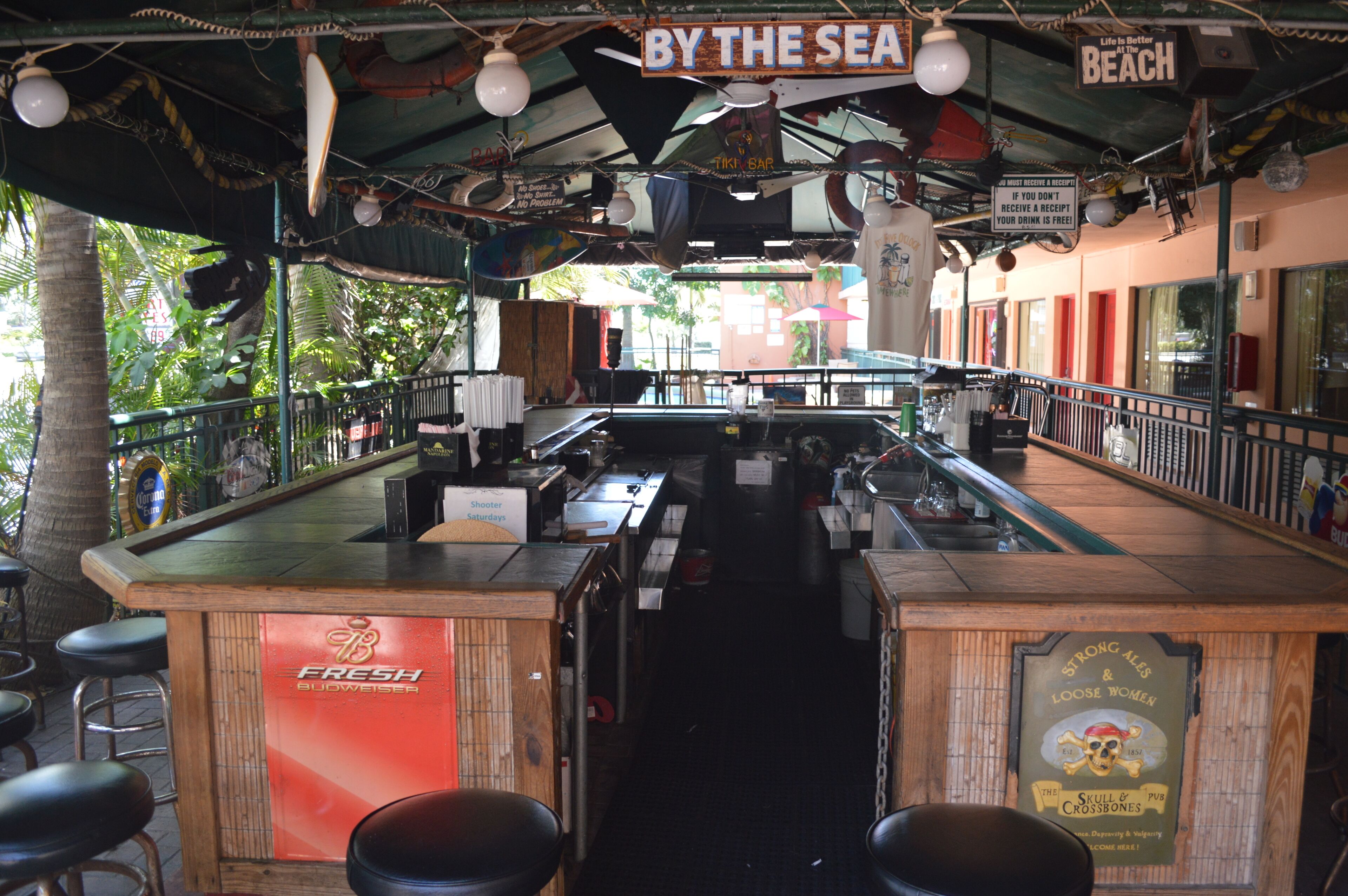 Uma área de bar com balcão, banquetas e um letreiro que diz 'BY THE SEA'.