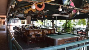 Ein Barbereich mit Billardtisch, Hockstühlen und einer Bar.