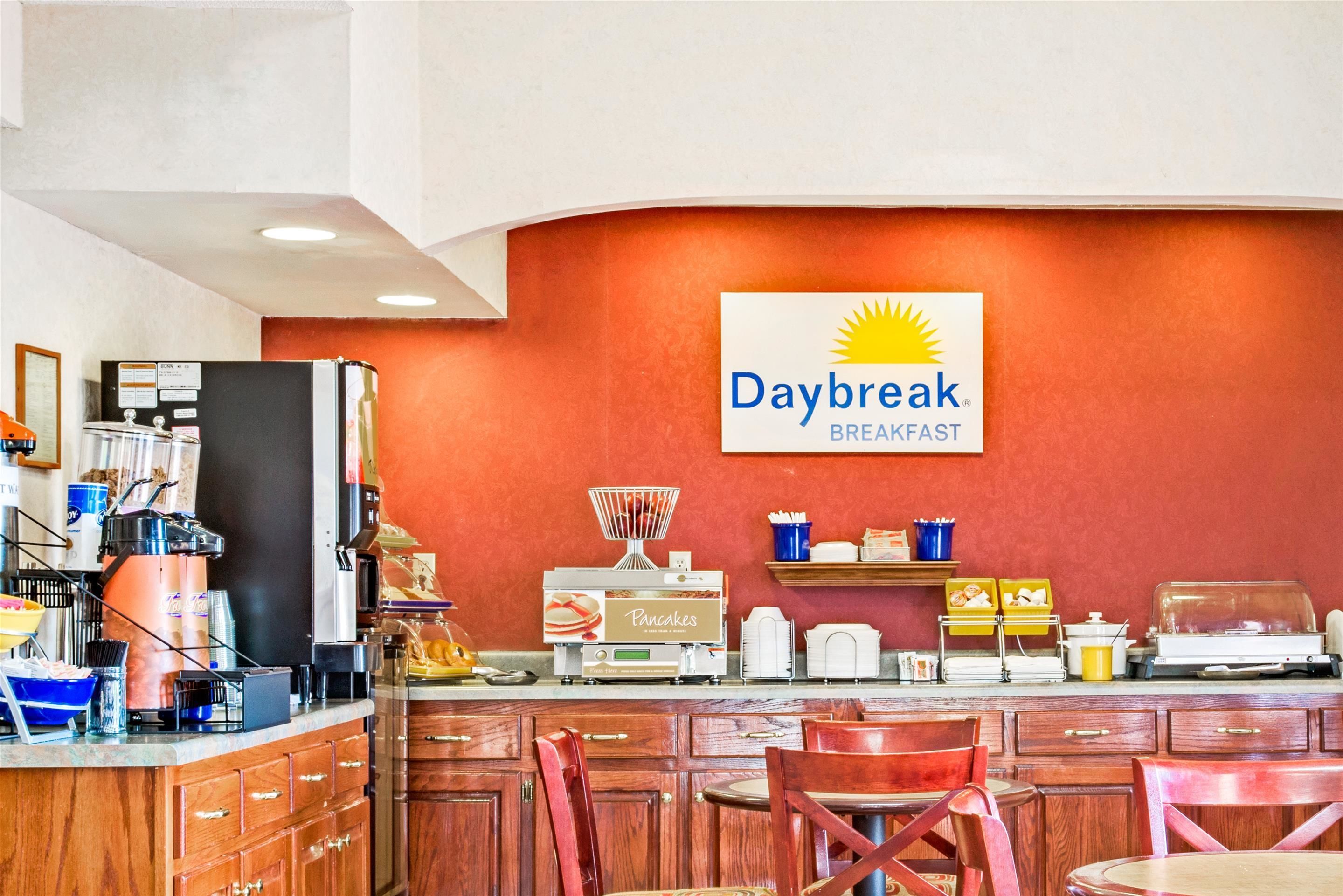 Ein Frühstücksbereich mit einem Daybreak Schild, einer Kaffeemaschine und verschiedenen Frühstücksangeboten auf der Theke.