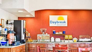 Ein Frühstücksbereich mit einem Daybreak Schild, einer Kaffeemaschine und verschiedenen Frühstücksangeboten auf der Theke.