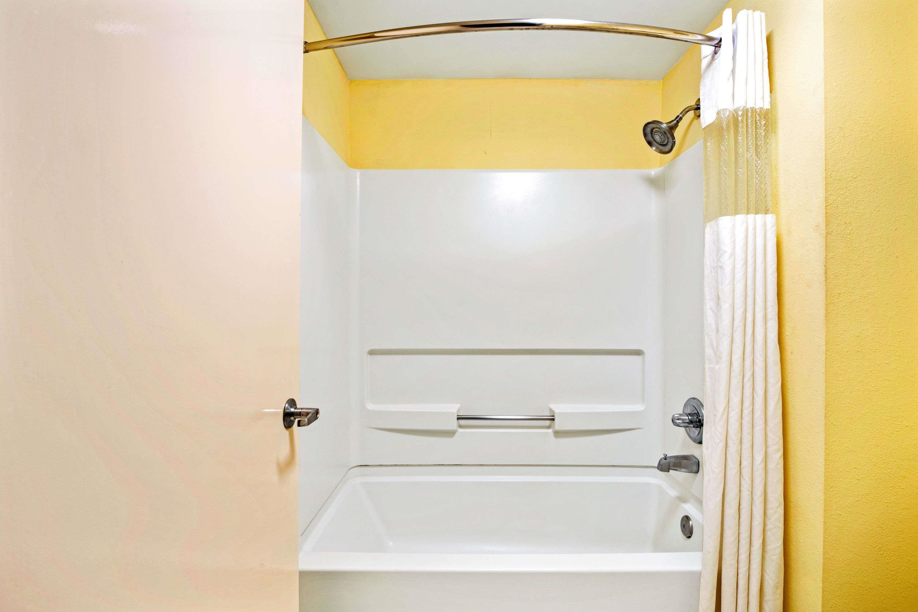 A bathroom with a bathtub, a shower curtain, and a towel rack.