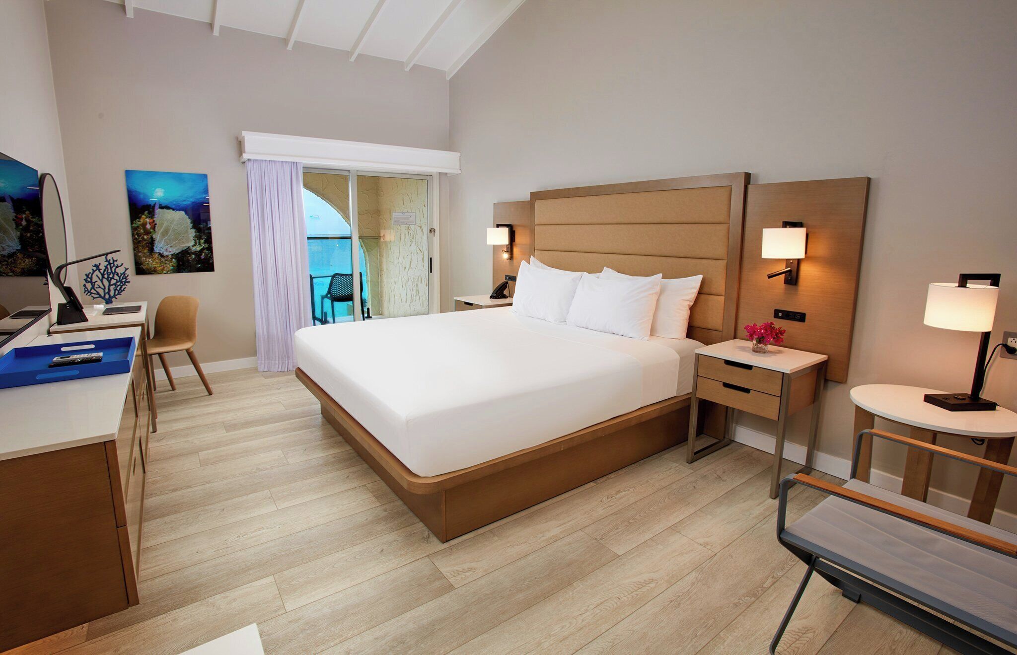 Une chambre d’hôtel avec un grand lit, des tables de chevet, un bureau avec une chaise et une vue sur l’extérieur.