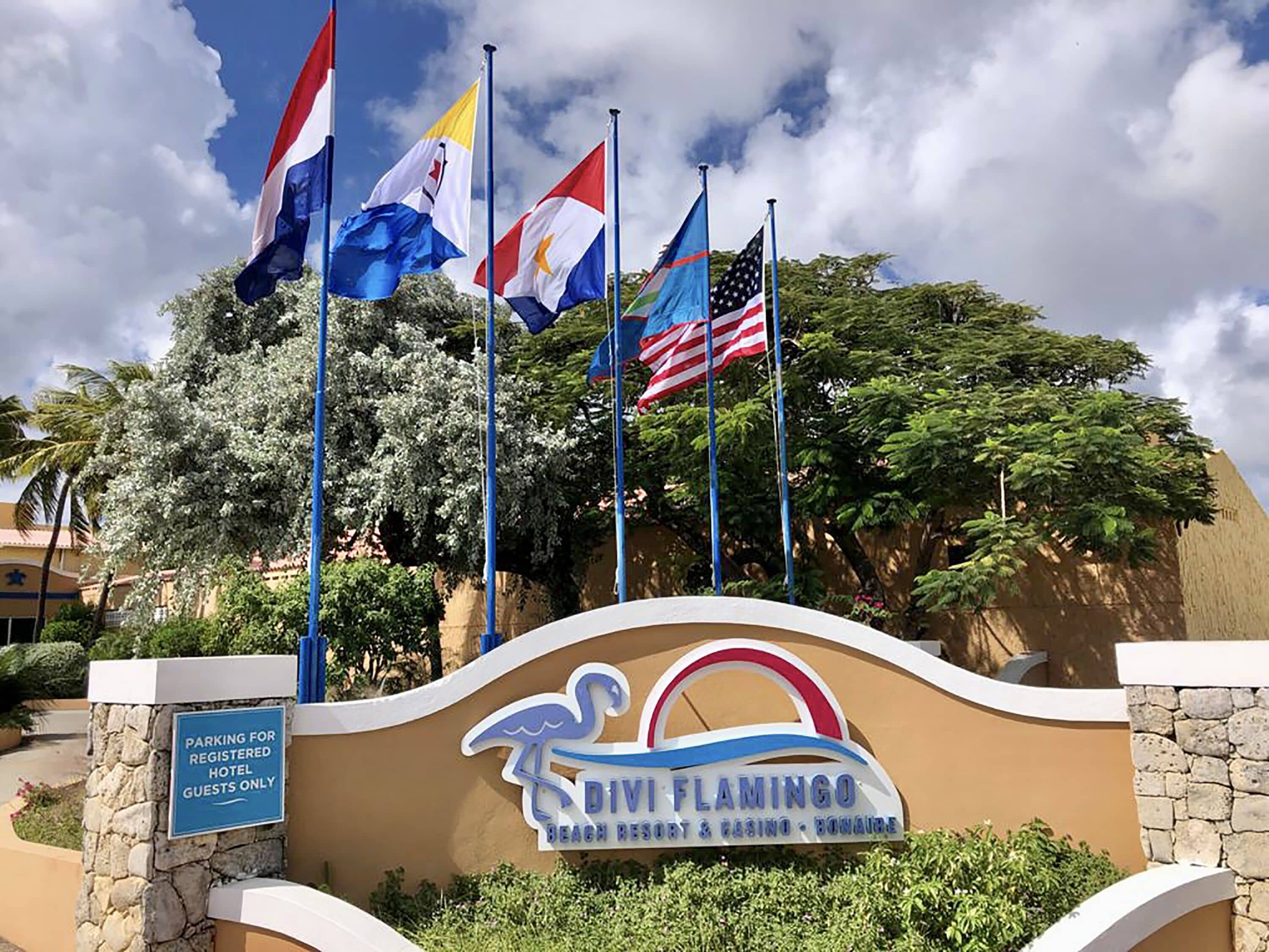 La entrada al Divi Flamingo Beach Resort & Casino con banderas de Estados Unidos, Filipinas y otros países.