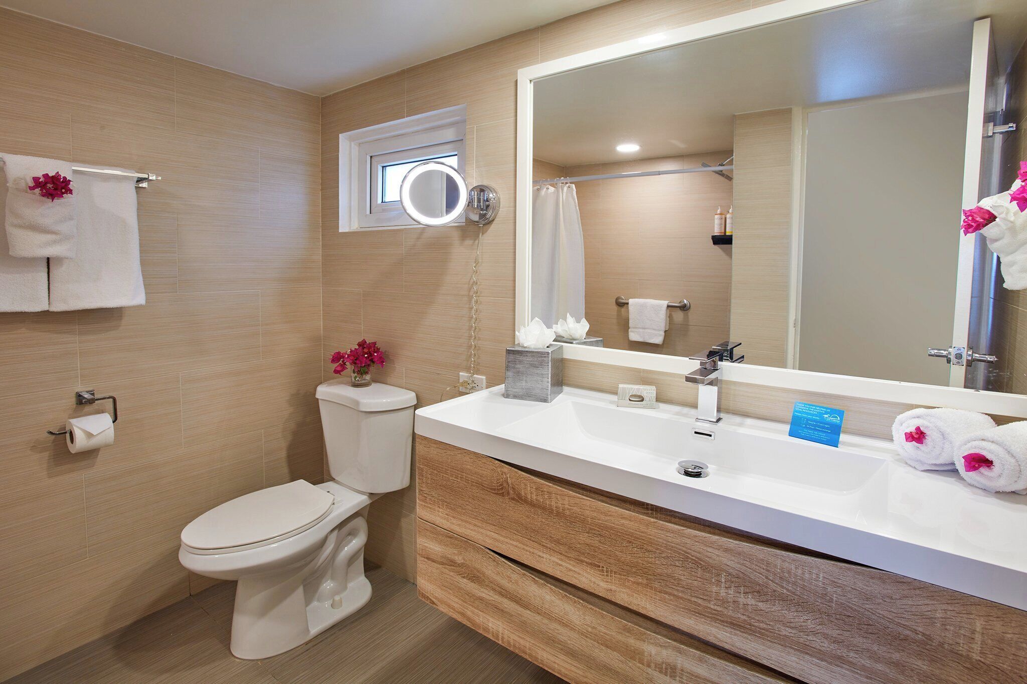 Un baño moderno con inodoro, lavamanos, espejo y toallero.