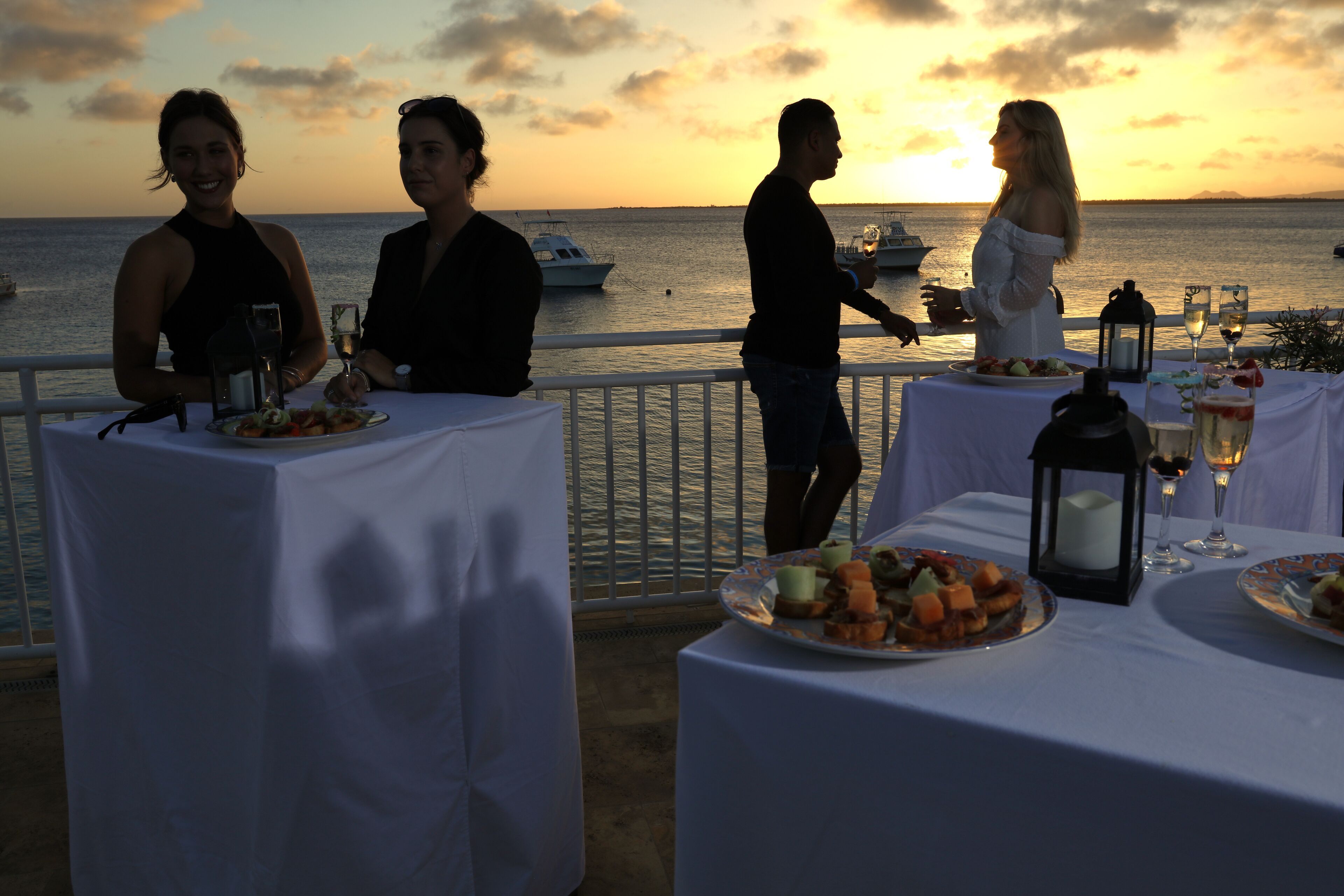 A sunset view with tables set for a meal, overlooking the sea.