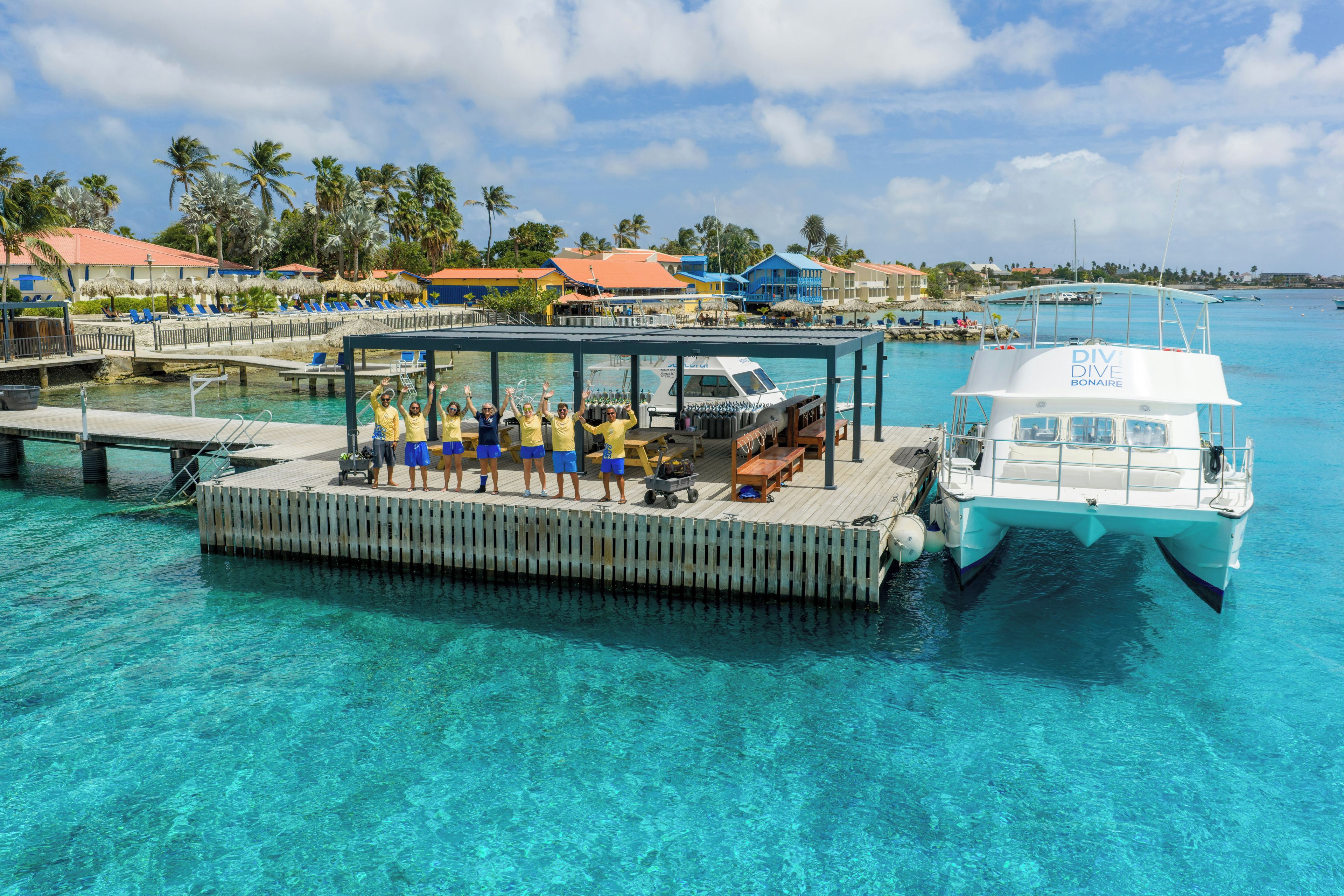 A boat docked at a pier with a group of people on a covered deck.