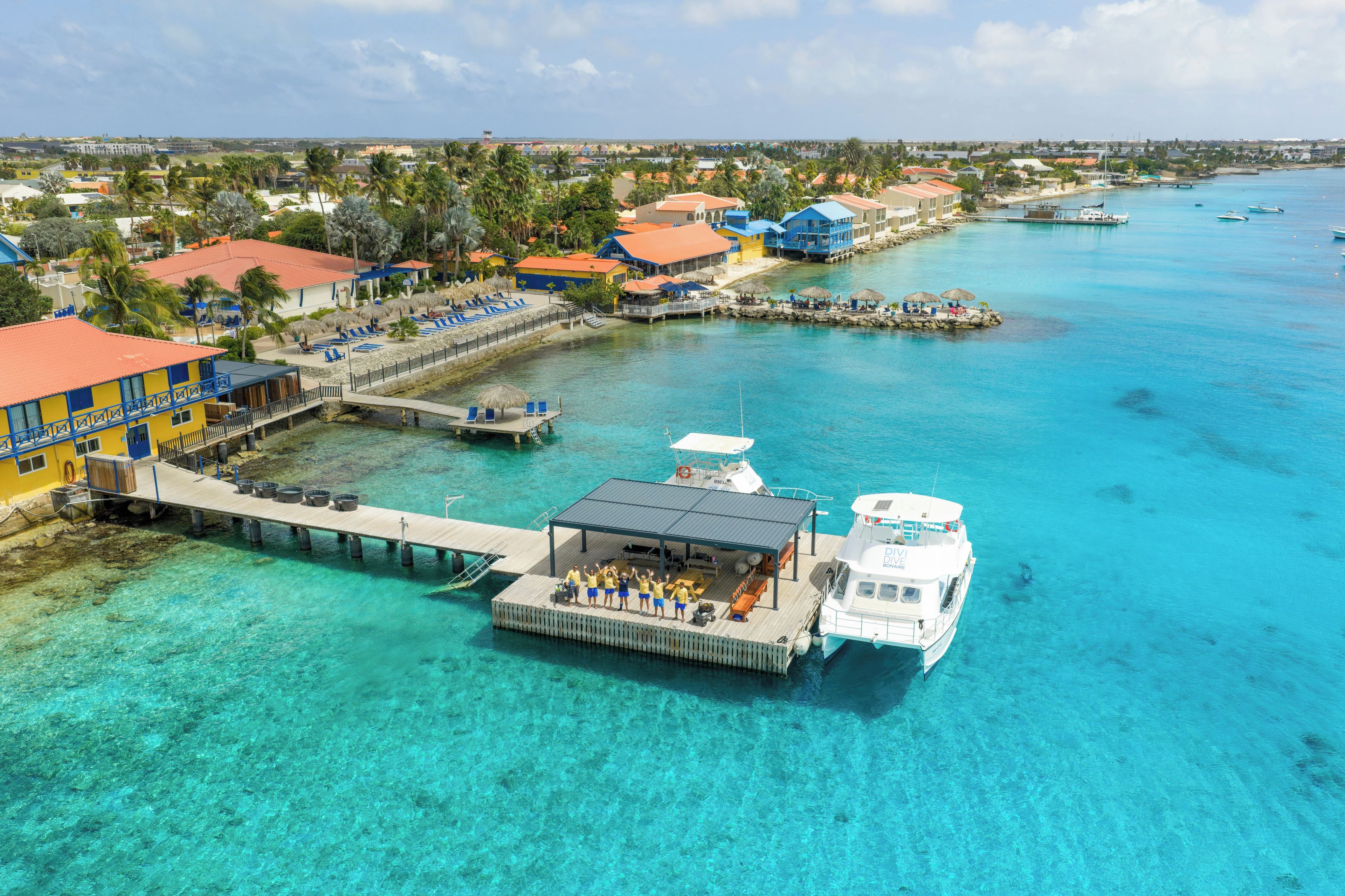 A coastal resort with a pier, clear turquoise waters, and a boat docked at the pier.
