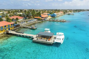 A coastal resort with a pier, clear turquoise waters, and a boat docked at the pier.