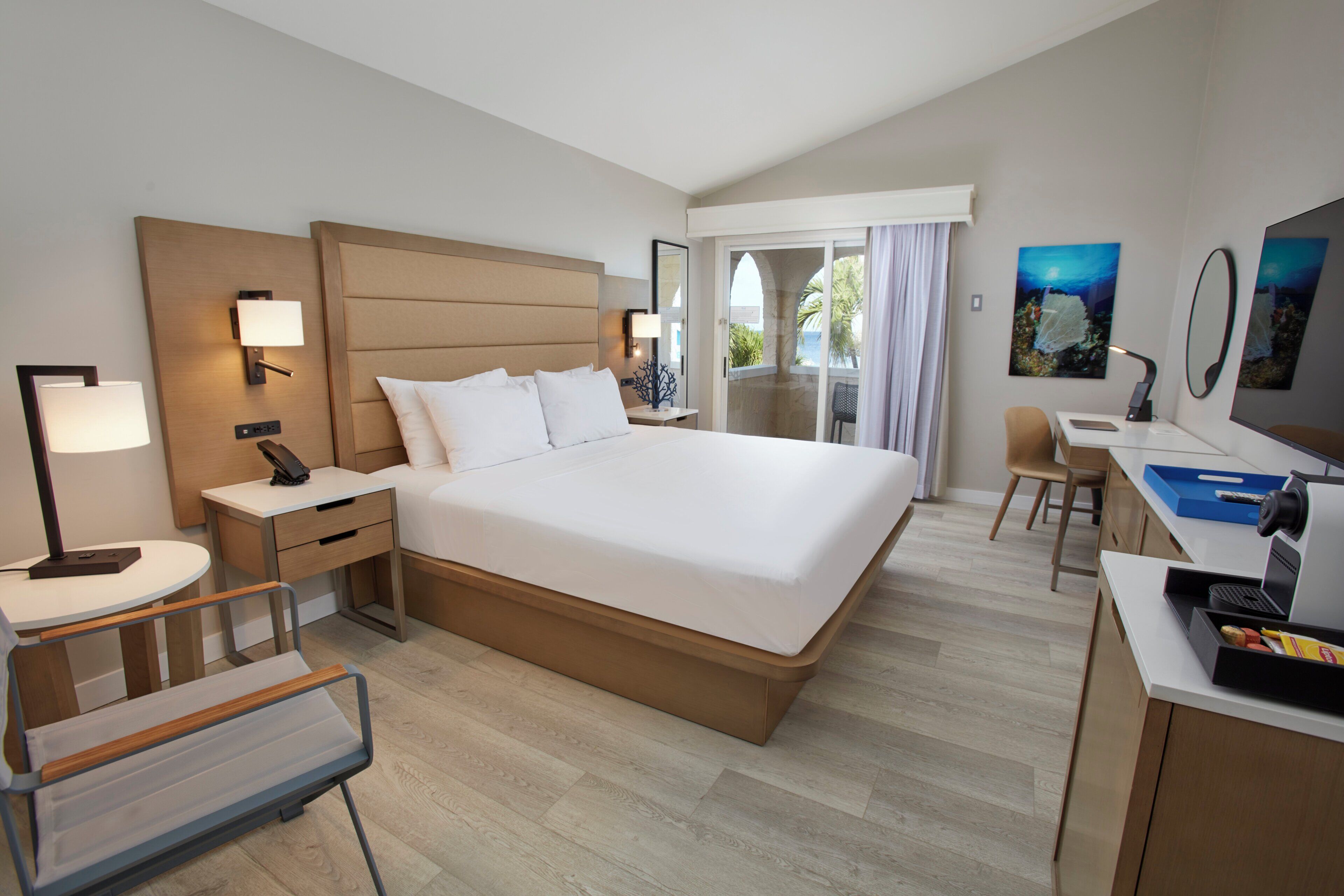A hotel room with a large bed, bedside tables, a desk, and a chair.