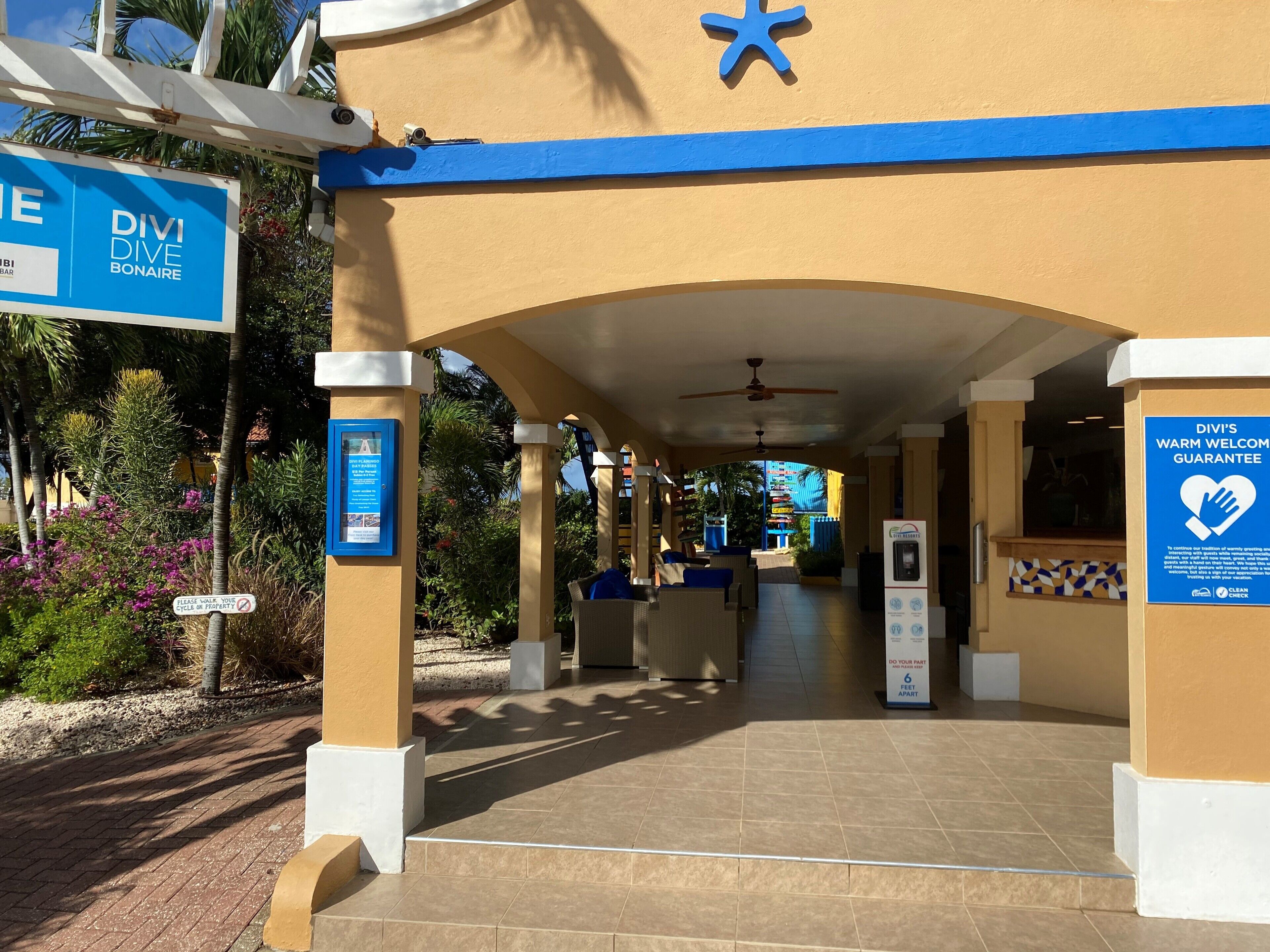A hotel entrance with a blue and beige color scheme, a covered walkway, and signs indicating amenities and services.
