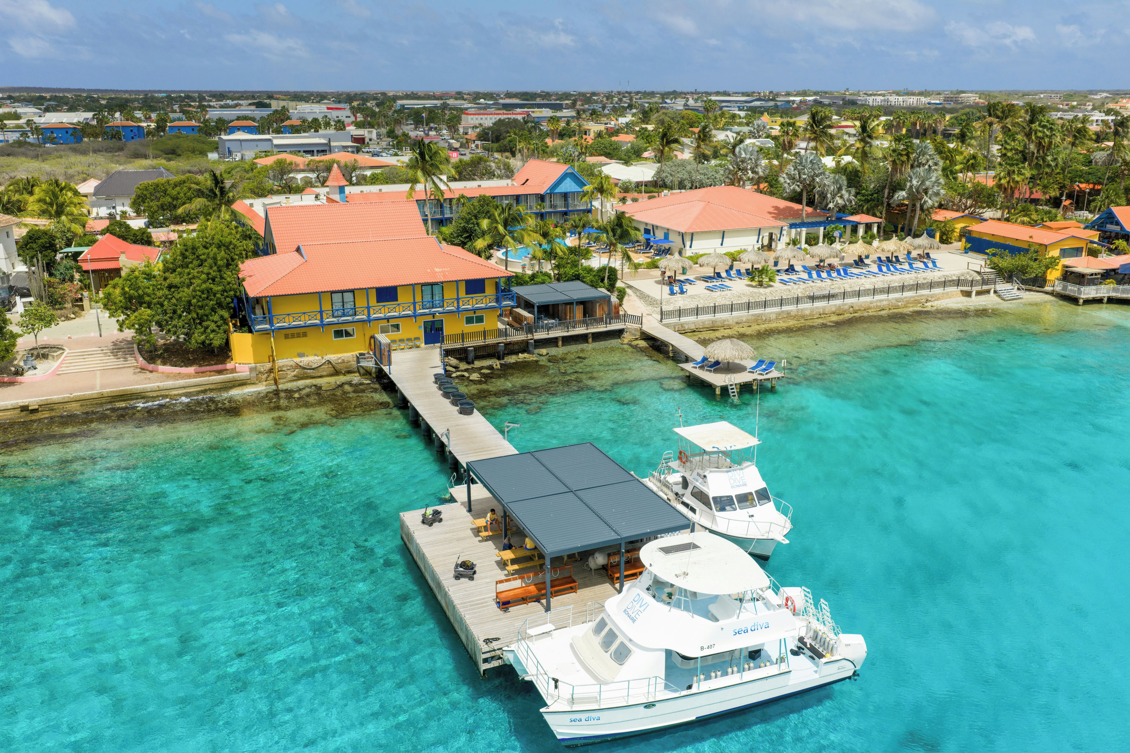 A coastal resort with a pier, a boat docked at the pier, and a clear turquoise sea.