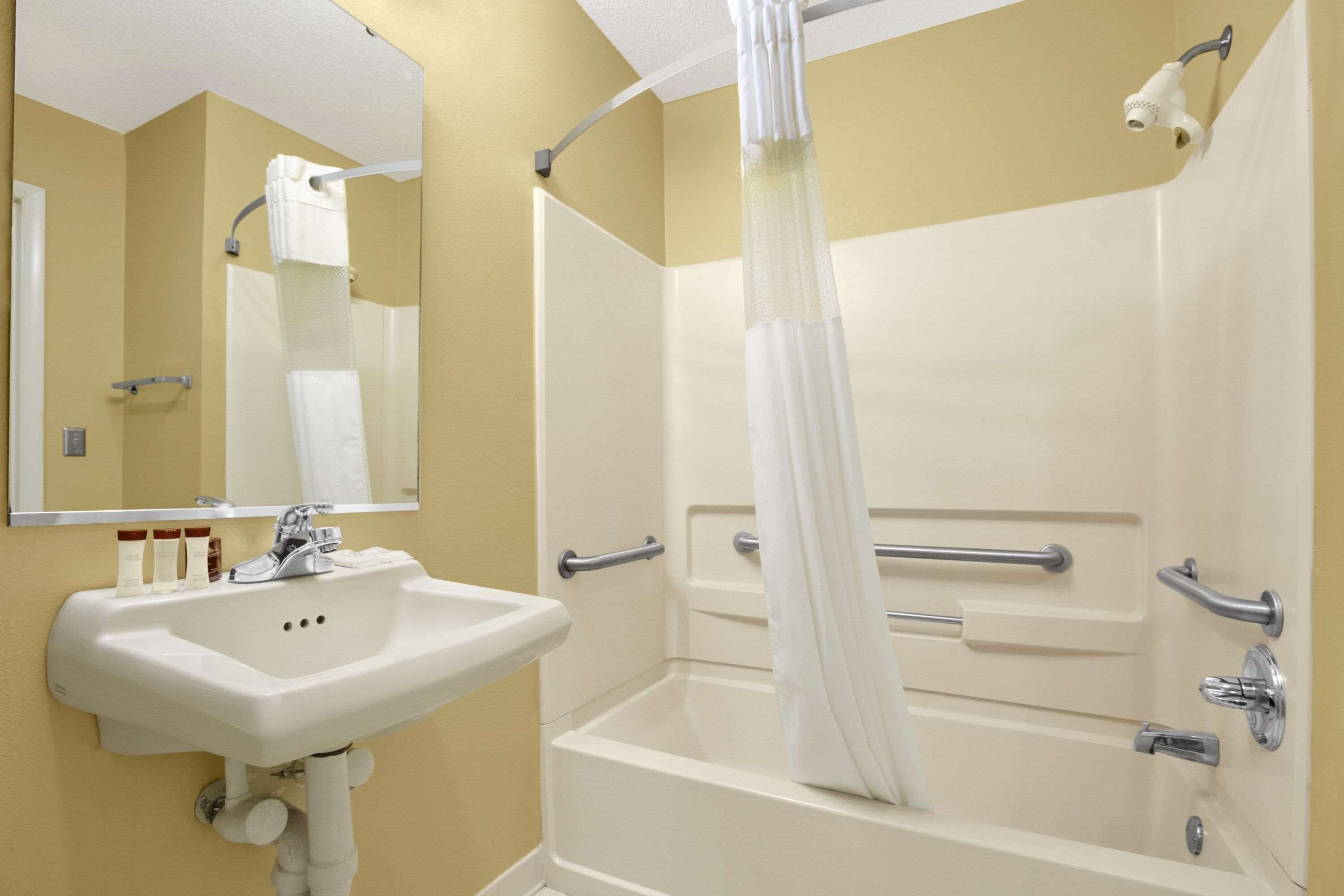 Un baño con lavamanos blanco, espejo y bañera.