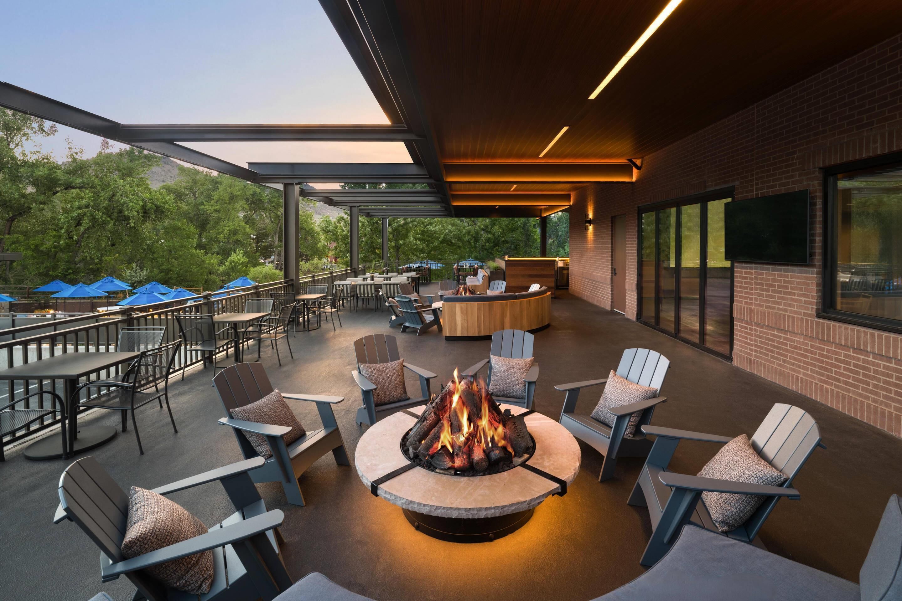 Eine Außenpatio-Terrasse mit Feuerstelle, Sitzgelegenheiten und Blick auf die umliegende Grünfläche.