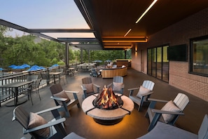 An outdoor patio area with a fire pit, seating, and a view of the surrounding greenery.