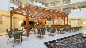 A spacious indoor area with multiple levels, wooden pergola structures, and a variety of seating arrangements including tables and chairs.