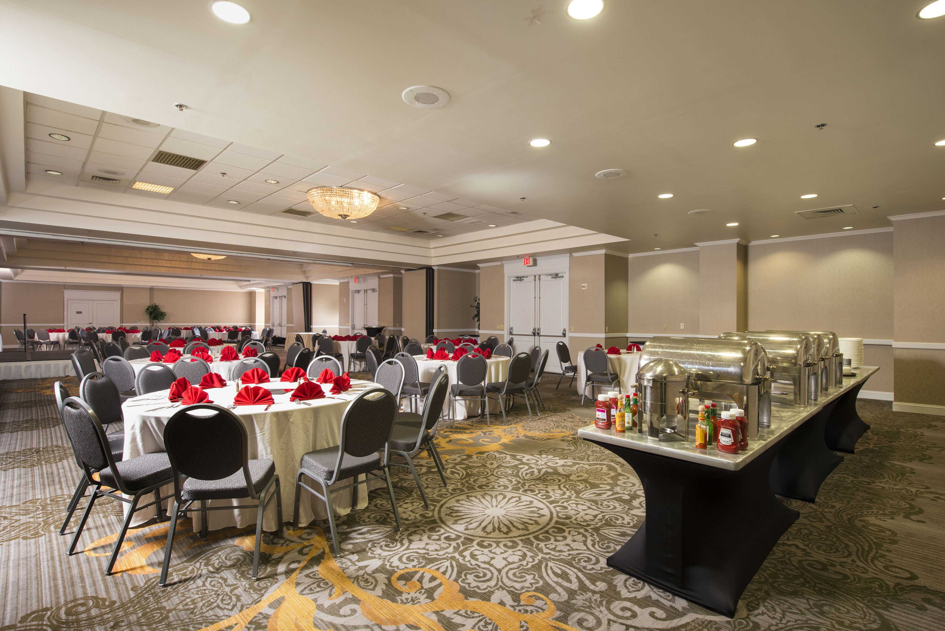 Un salón de banquetes con mesas redondas, sillas y una zona de bufé.
