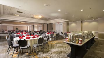 Un salón de banquetes con mesas redondas, sillas y una zona de bufé.