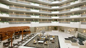 A multi-level hotel atrium with balconies, seating areas, and a central water feature.