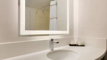 Une salle de bain avec un lavabo blanc, un miroir et un rideau de douche.