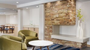 Un interior moderno con un muro de acento de piedra, una mesa redonda blanca y sillones verdes.
