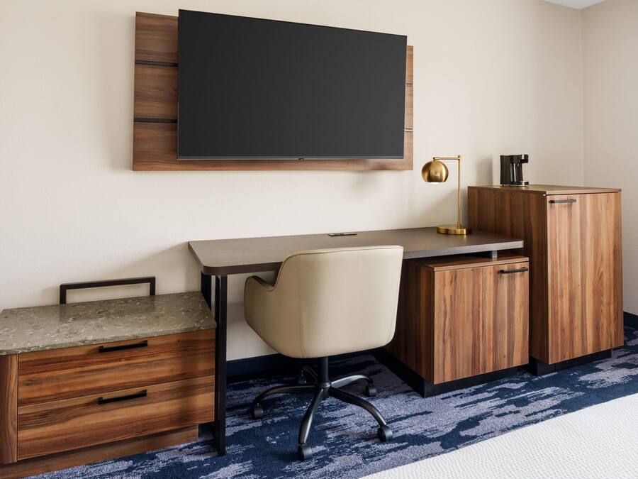 A modern office space with a desk, chair, and a mounted flat-screen TV.