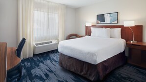 A hotel room with a large bed, a desk, a chair, a window with sheer curtains, a wall-mounted air conditioner, and a painting above the bed. - Fairfield Inn by Marriott Huntsville (Huntsville)
