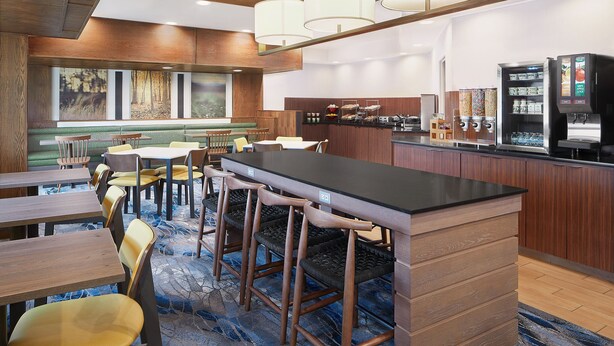 A modern hotel lobby with a bar area, seating arrangements, and a view of the outdoors. - Fairfield Inn by Marriott Huntsville (Huntsville)