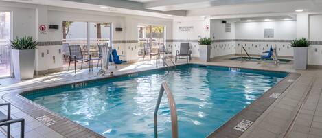 An indoor swimming pool with clear water, surrounded by lounge chairs and a sun deck.
