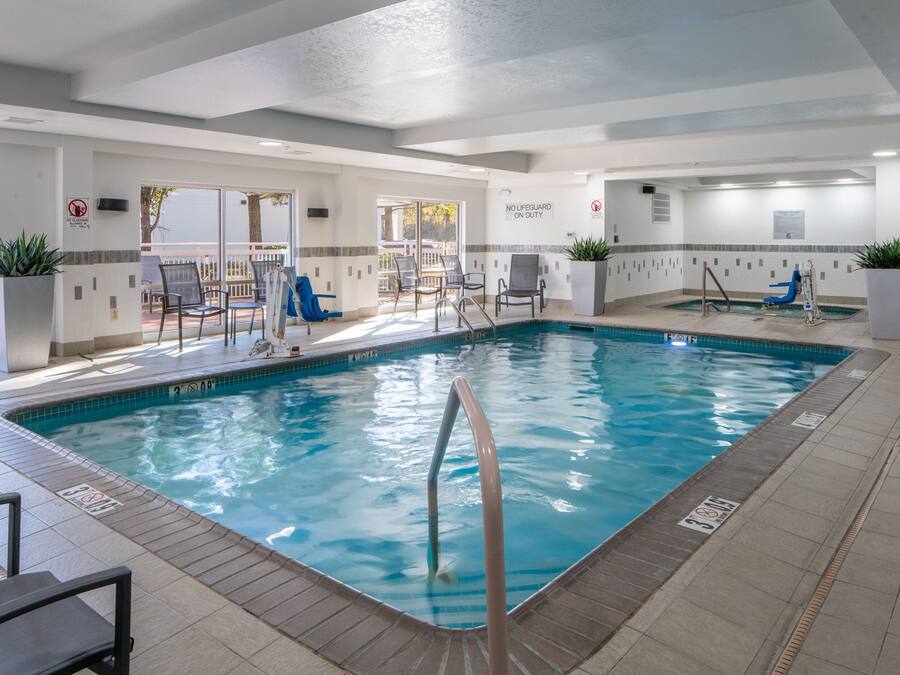 An indoor swimming pool with clear water, surrounded by lounge chairs and a sun deck.