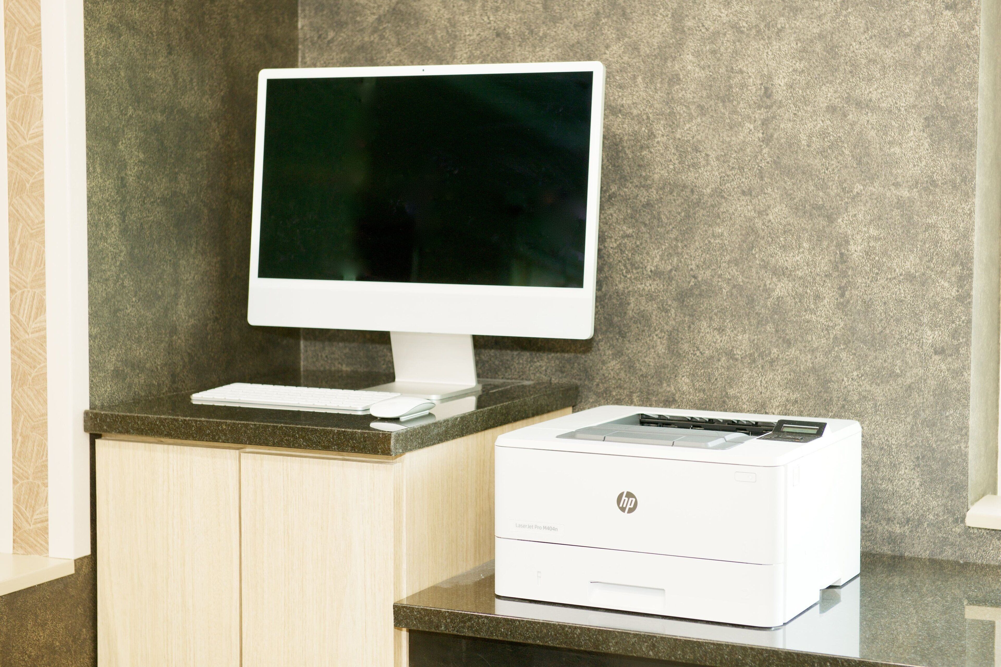 A desktop computer with a monitor and printer on a counter.