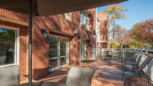An outdoor patio with brick walls, metal chairs, and a table. - Fairfield Inn & Suites By Marriott Memphis Germantown (Germantown)