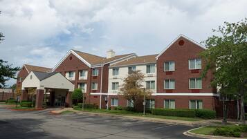 A multi-story hotel with a brick facade, a covered entrance, and a parking lot.