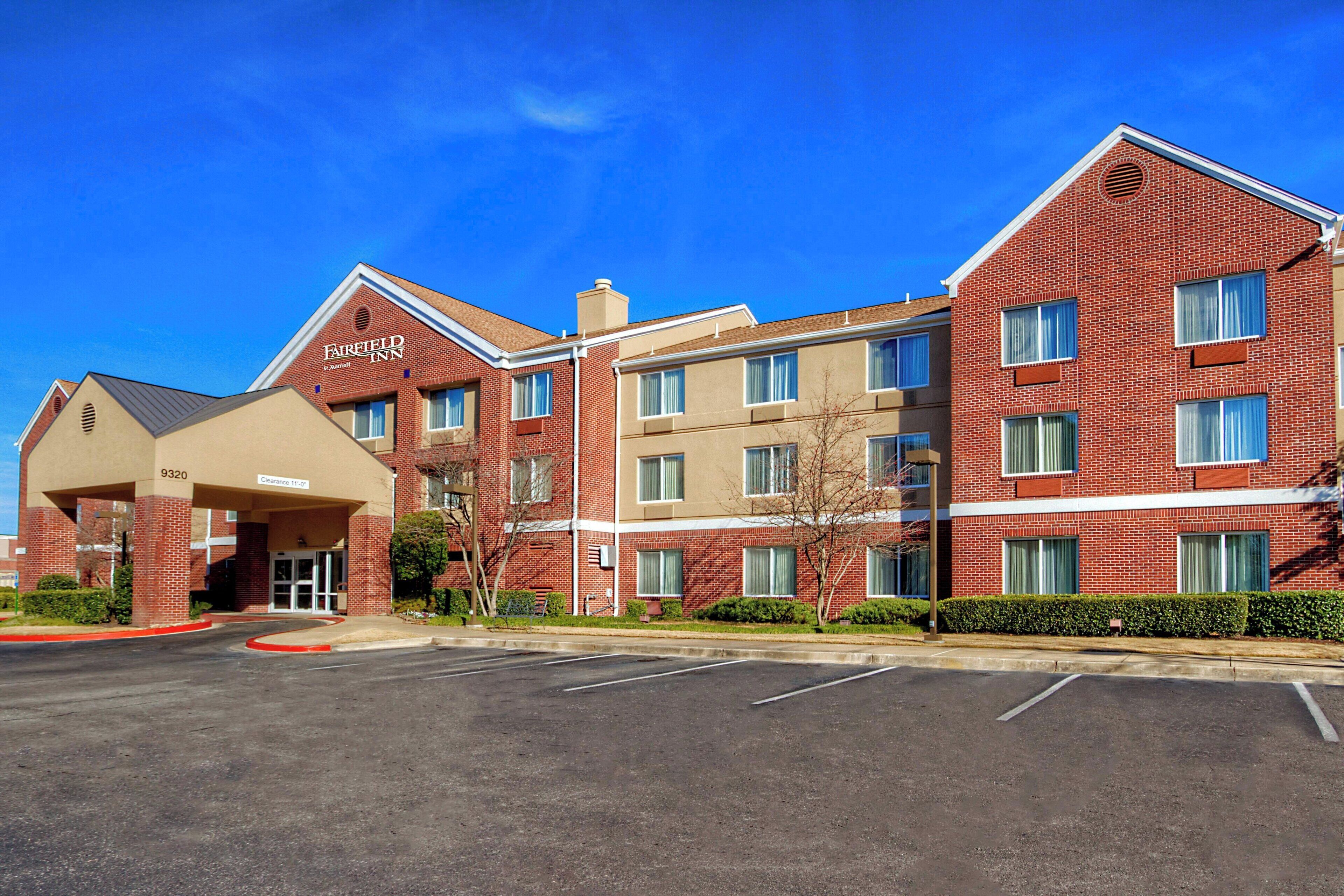 A multi-story hotel with a brick facade, a covered entrance, and a parking lot.
