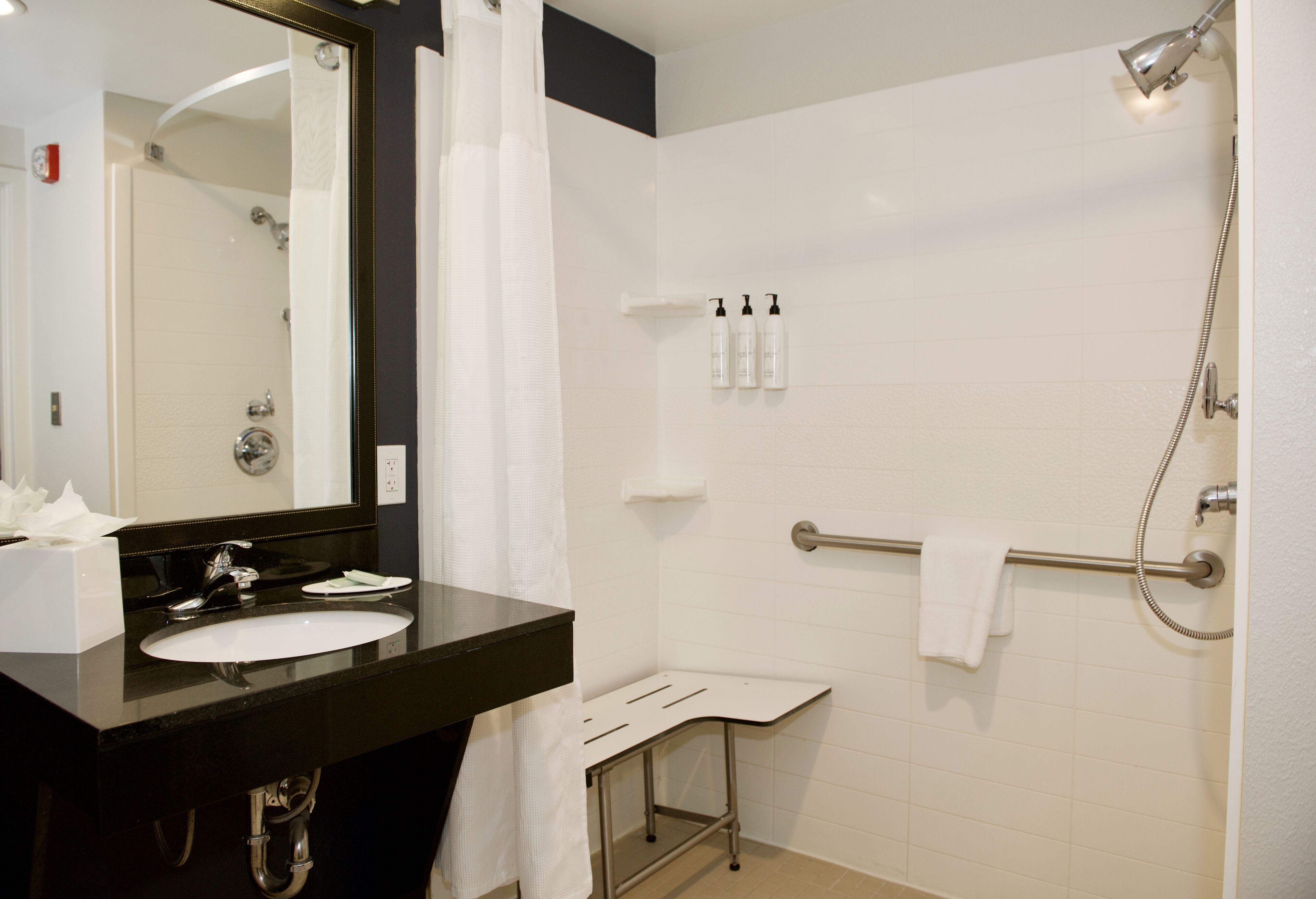 Une salle de bain équipée d’un lavabo, d’un miroir, d’une douche et d’un porte-serviettes.