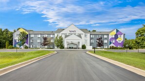 A multi-story hotel with a central entrance, surrounded by well-maintained lawns and a clear sky.