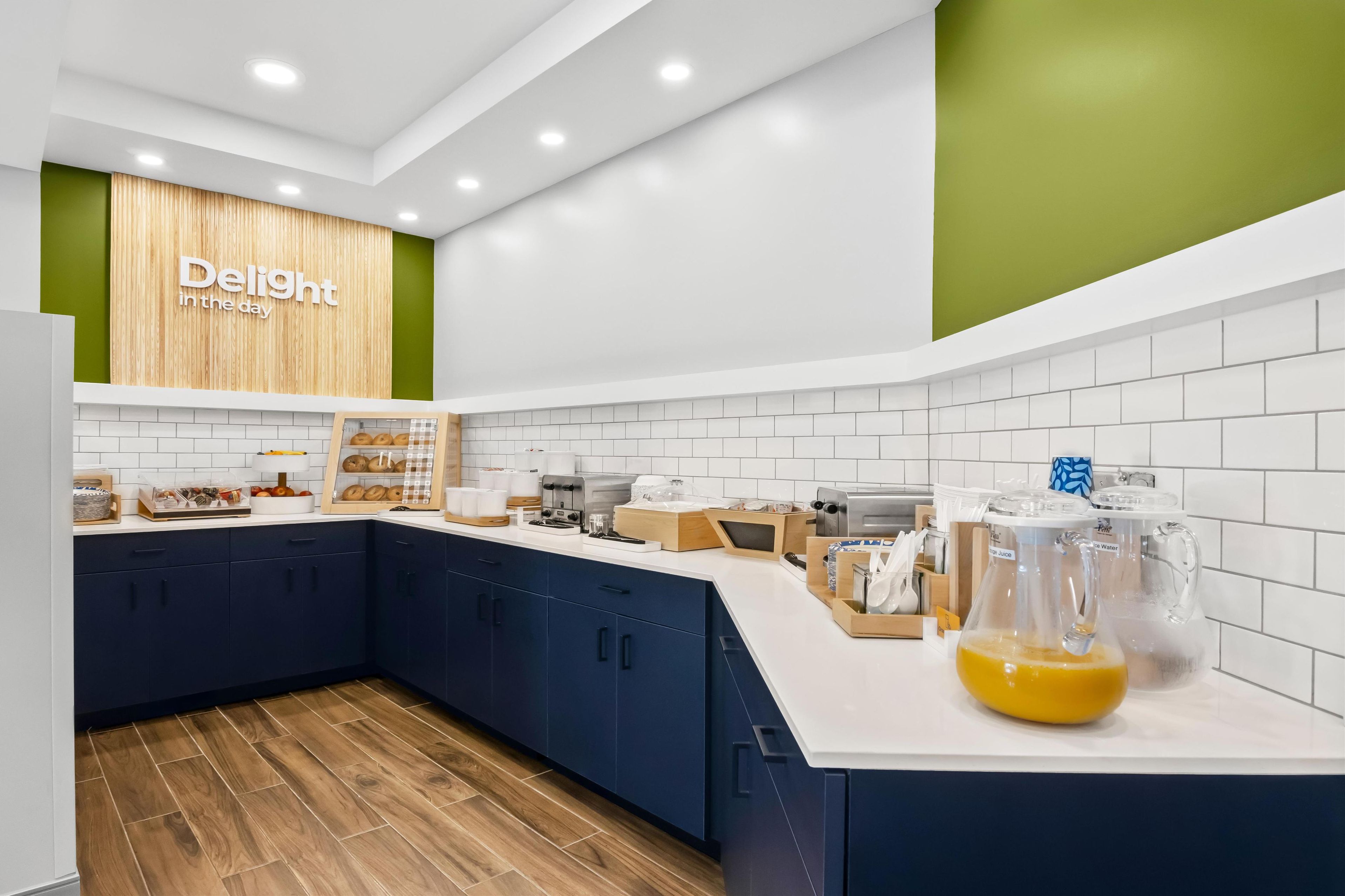 A modern kitchen with dark blue cabinets, white countertops, and a wooden floor.