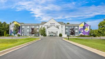 A multi-story hotel with a central entrance, surrounded by well-maintained lawns and a clear sky.