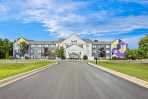 A multi-story hotel with a central entrance, surrounded by well-maintained lawns and a clear sky. - Spark by Hilton Traverse City (Traverse City)