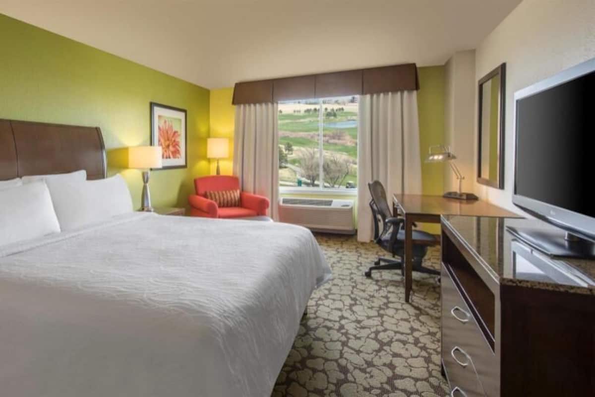 Een hotelkamer met een groot bed, een bureau, een stoel, een televisie en een raam met uitzicht.