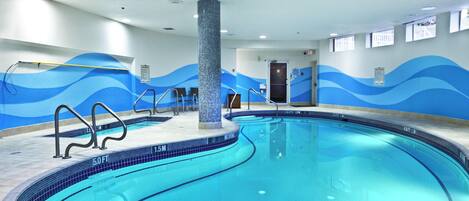 An indoor swimming pool with a tiled edge, a central column, and wave-patterned walls.