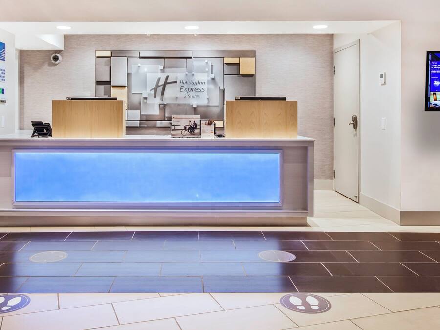 Een hotel receptie met een digitaal scherm waarop nieuws en evenementen worden getoond, een receptiebalie en een bord dat aangeeft dat alcoholische dranken niet zijn toegestaan in openbare ruimtes.